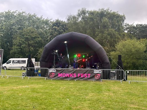 6x4 meter inflatable stage A stage setup with band equipment, surrounded by greenery and barriers.