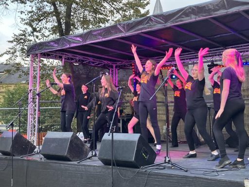 6x4 custom build stage A group of singers performing energetically on stage with raised arms.